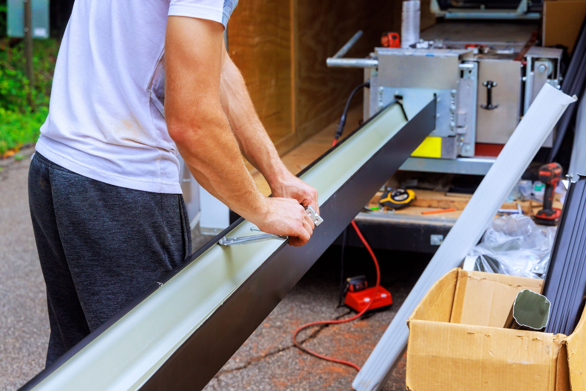 An employee is installing hidden gutter hangers with pre installed screw before attaching new gutter to a roof.